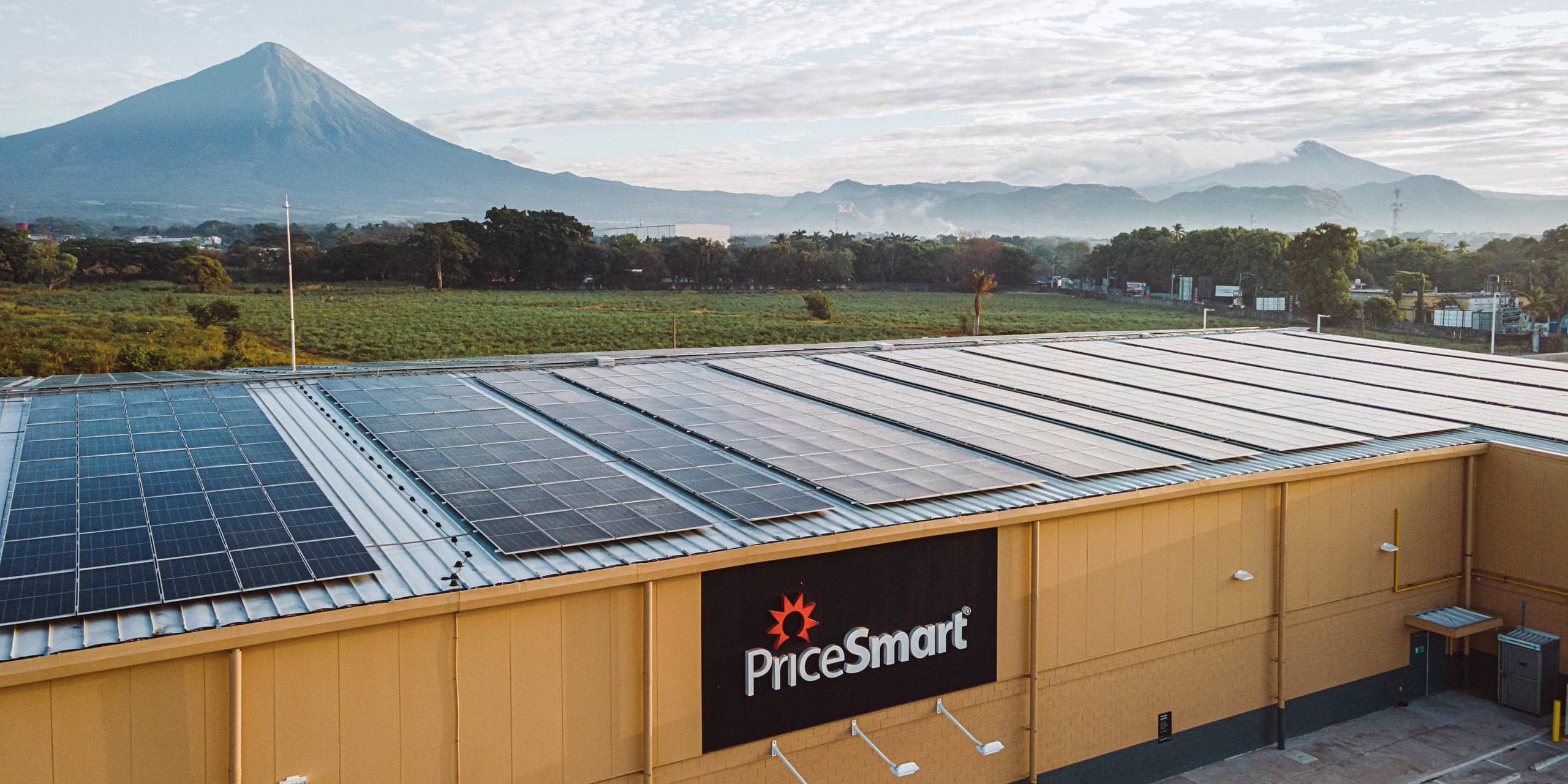 A PriceSmart warehouse club with a rooftop solar array, mountains behind